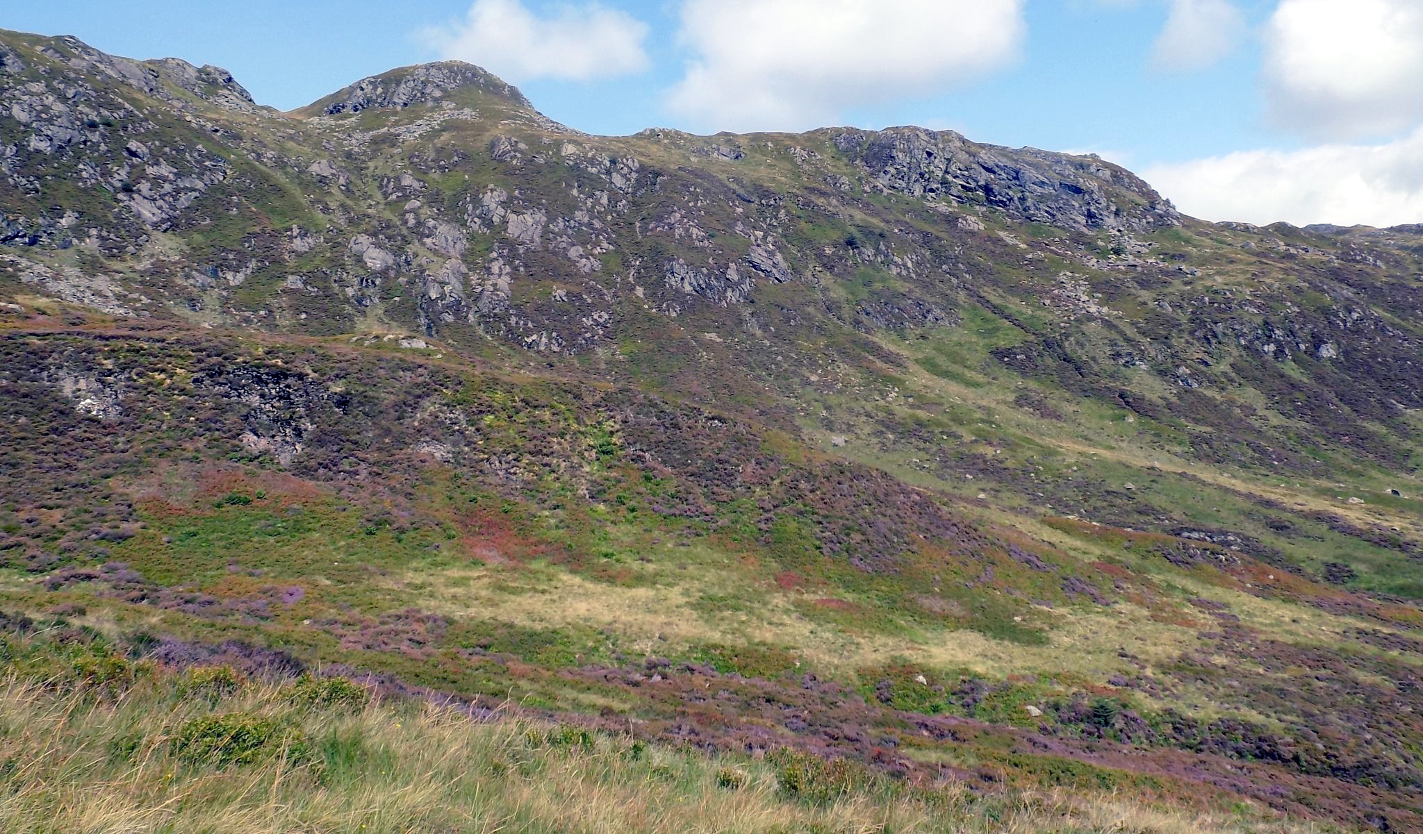 Heather covered hillsides beneath rock crags of Stank Glen on descent from Ben Ledi